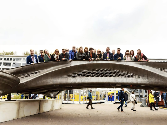 A picture of Robin on a 3D printed bridge, guiding a large crowd through Dutch Design Week